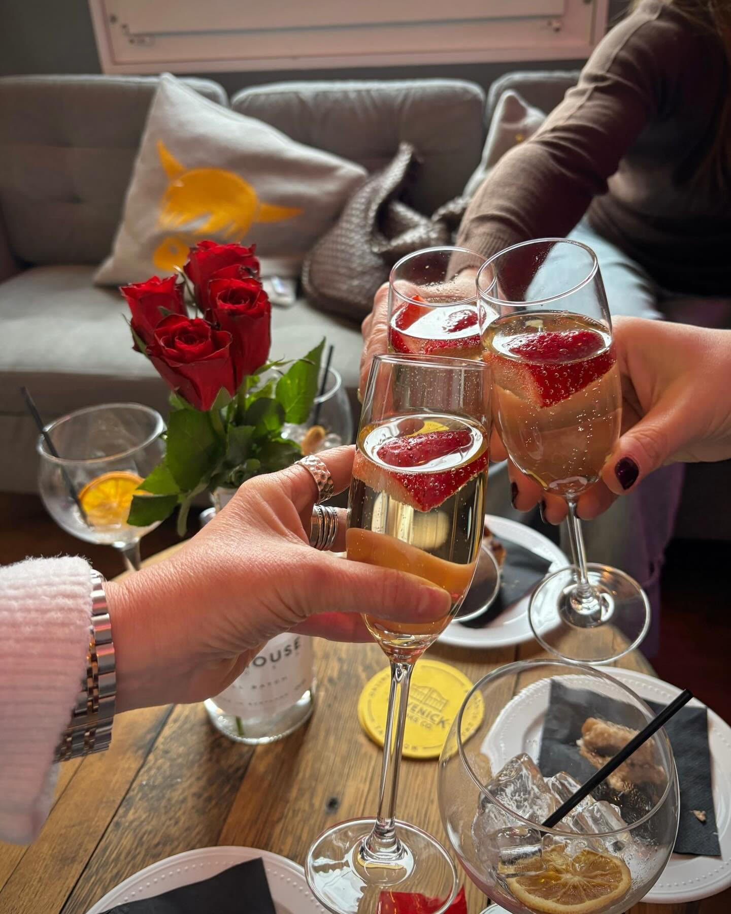 Friends clinking cocktails across a table of drinks