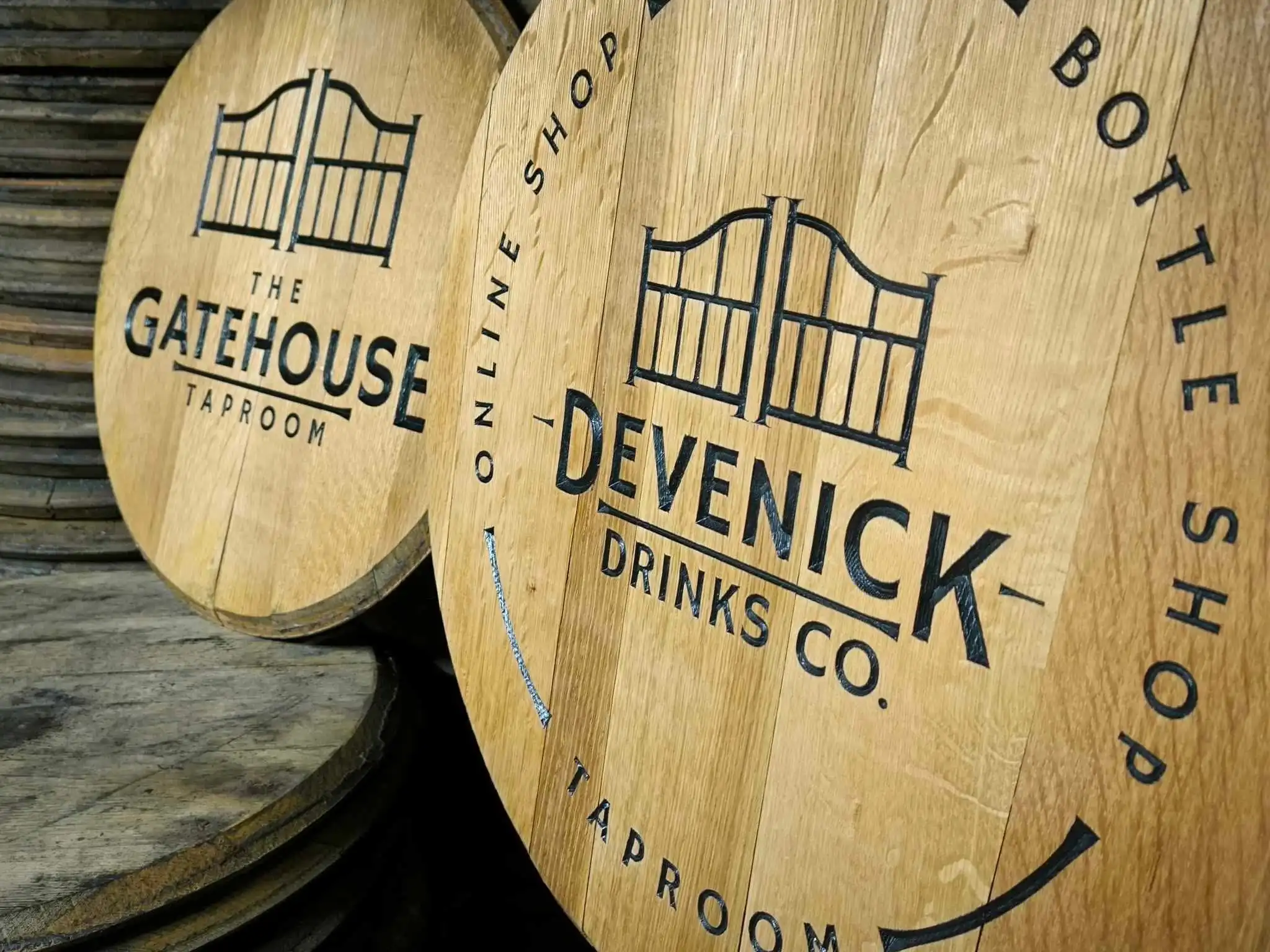 Wooden barrel lids branded with the Gatehouse Taproom and Devenick Drinks Co. gate logos